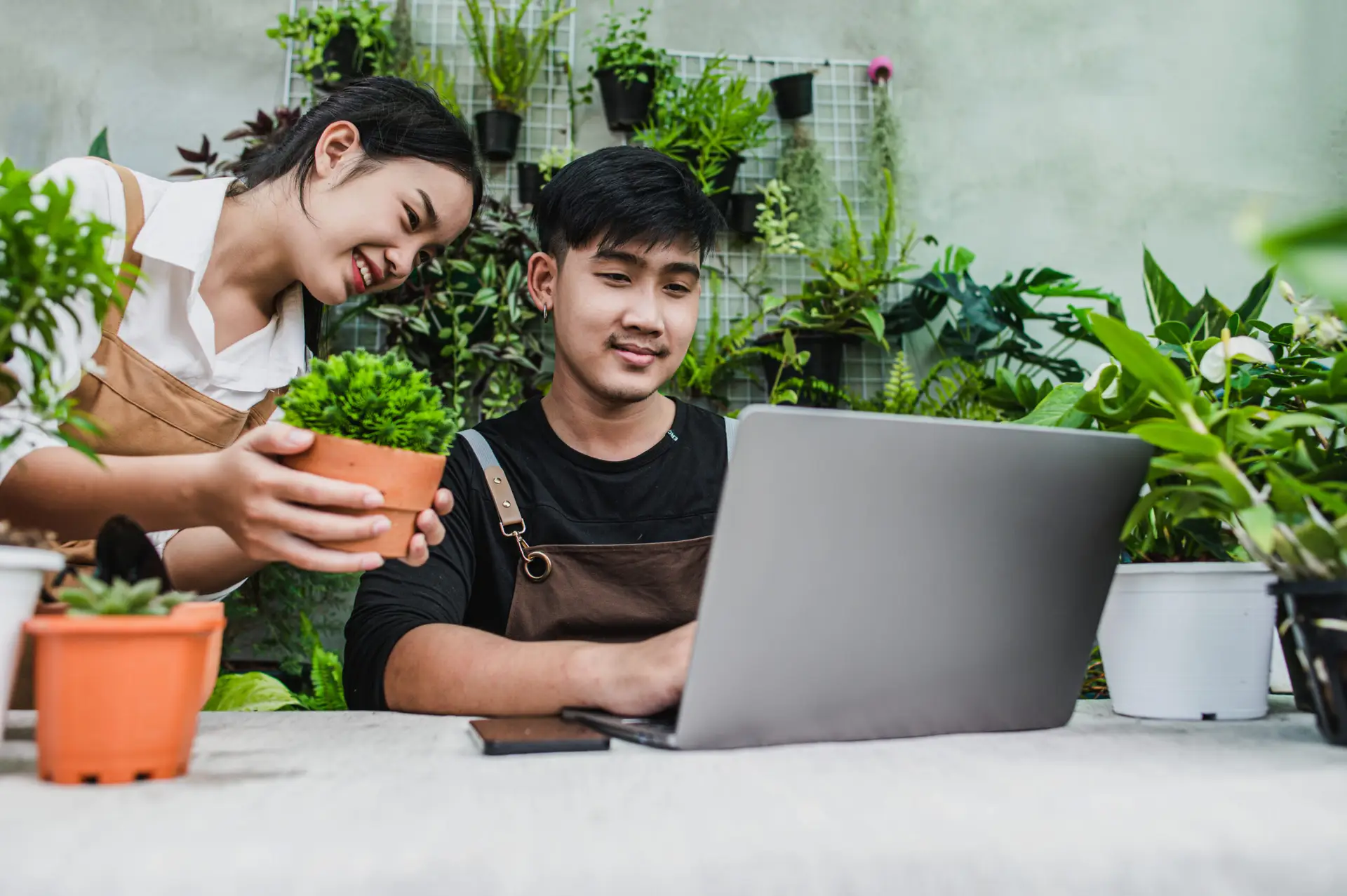 Lawn care professionals managing jobs on a phone and laptop outdoors
